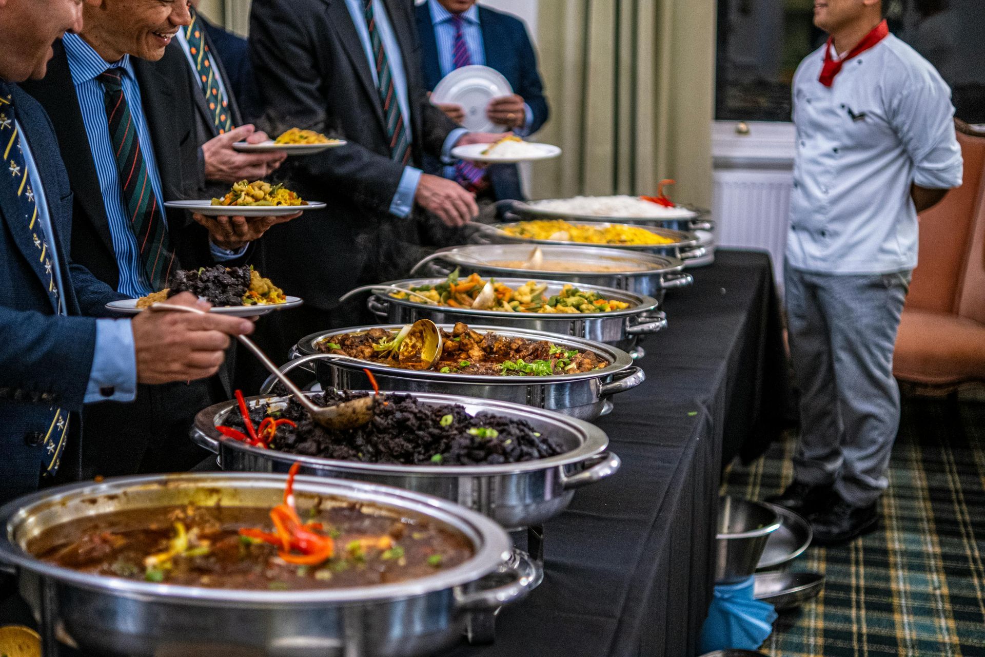 Buffet line with covered dishes and guests serving themselves at a catered event
